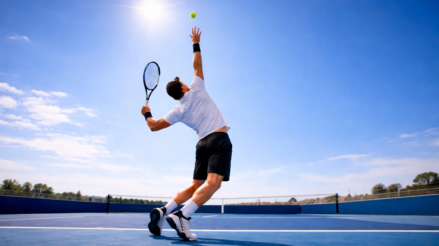 Nahaufnahme eines Tennisaufschlags mit Ballwurf vor blauem Himmel